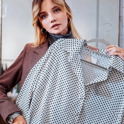 cintre anti-glisse femme tient une chemise Ă pois cintre