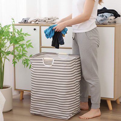 femme dépose linge sale dans panier a linge rayé