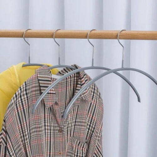 Cintre essentiels gris accroché à une penderie avec une chemise jaune l'autre à carreaux