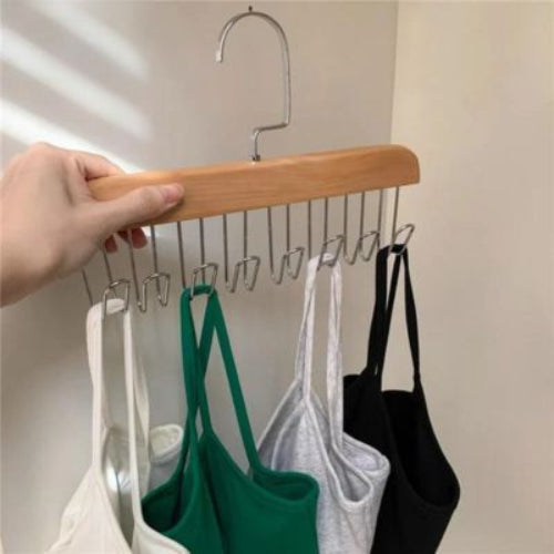 Cintre soutien gorge bois clair une main tient le cintre ou sont accroches des soutiens gorge et top a bretelle blanc vert gris et noir