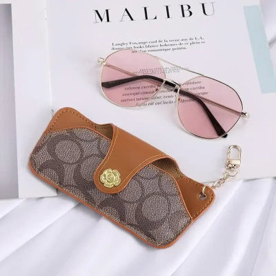 étui à lunette fermé marron pose sur magazine