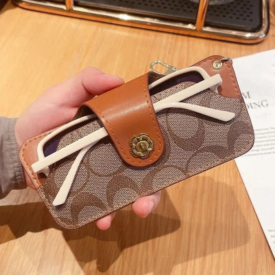 etui a lunette marron fermoire fleur tenu dans main femme