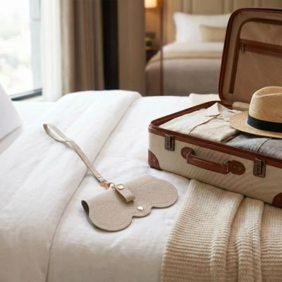 étui à lunettes posé sur un lit à côté valise 