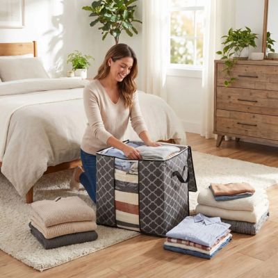 femme rempli sac de rangement vetement accroupi pres lit