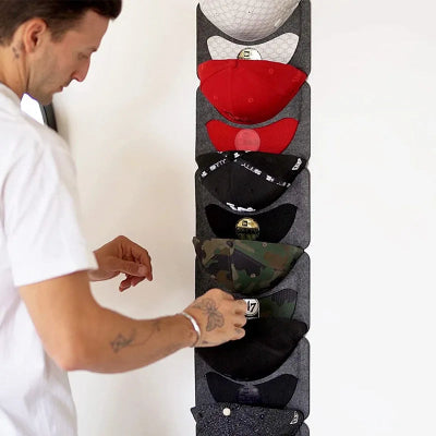 homme choisi casquette sur porte casquette mural 